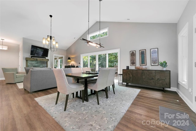 dining room with hardwood / wood-style flooring, a chandelier, and high vaulted ceiling