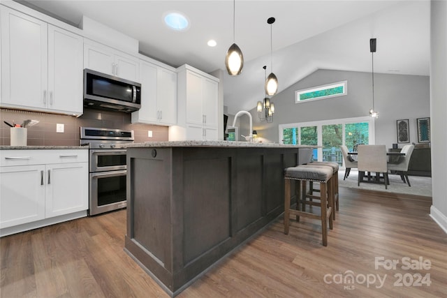 kitchen with white cabinets, appliances with stainless steel finishes, and pendant lighting