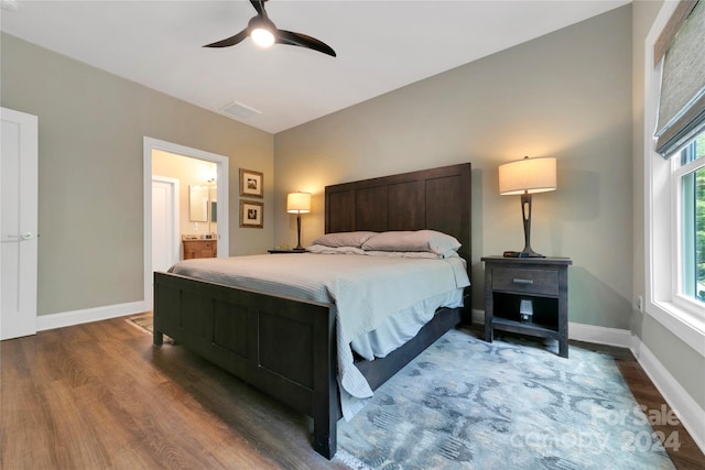 bedroom with ceiling fan, connected bathroom, and dark hardwood / wood-style flooring