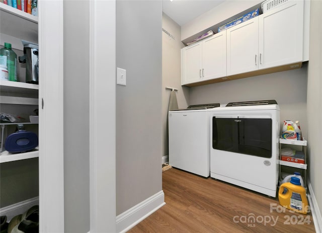 washroom featuring washer and clothes dryer, cabinets, and light hardwood / wood-style floors