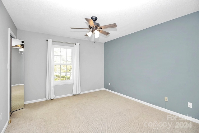 carpeted spare room featuring a textured ceiling and ceiling fan