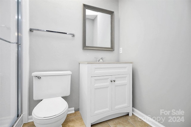 bathroom with tile patterned flooring, an enclosed shower, vanity, and toilet