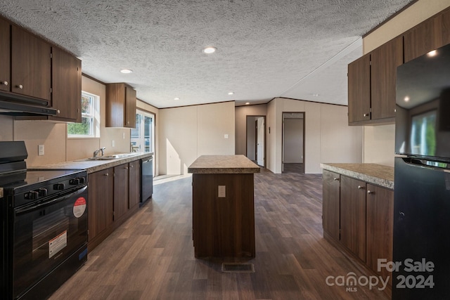 kitchen featuring a center island, a textured ceiling, black appliances, and dark hardwood / wood-style flooring