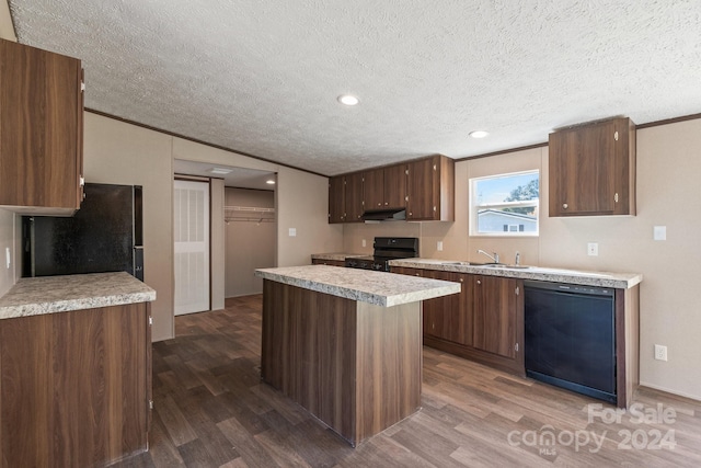 kitchen with black appliances, a kitchen island, a textured ceiling, dark hardwood / wood-style flooring, and crown molding