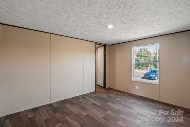 unfurnished room with a textured ceiling and dark wood-type flooring