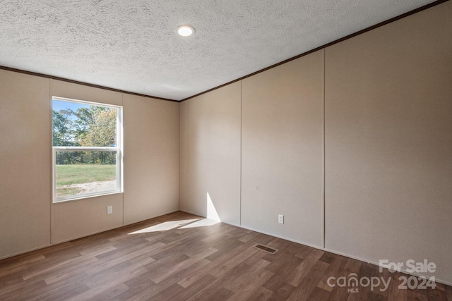 spare room featuring a textured ceiling, ornamental molding, and hardwood / wood-style floors