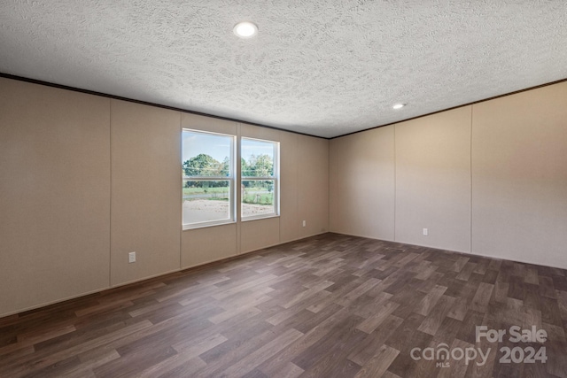 empty room with a textured ceiling and dark hardwood / wood-style flooring