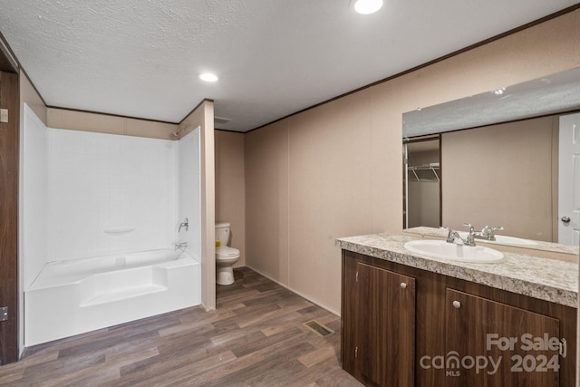 full bathroom featuring toilet, shower / bath combination, wood-type flooring, vanity, and a textured ceiling