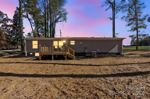 back house at dusk with a deck and cooling unit