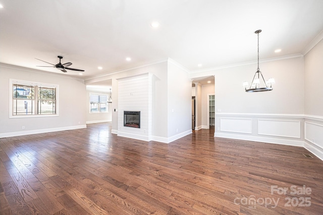 unfurnished living room with a glass covered fireplace, dark wood-style floors, ceiling fan with notable chandelier, crown molding, and recessed lighting