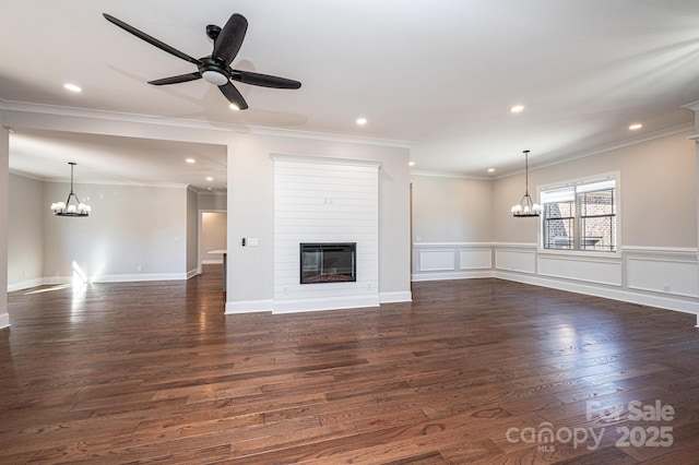 unfurnished living room featuring recessed lighting, a large fireplace, ceiling fan with notable chandelier, a decorative wall, and dark wood-style flooring