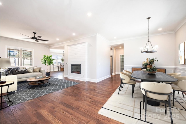 dining area featuring ornamental molding, dark wood-type flooring, a glass covered fireplace, and recessed lighting