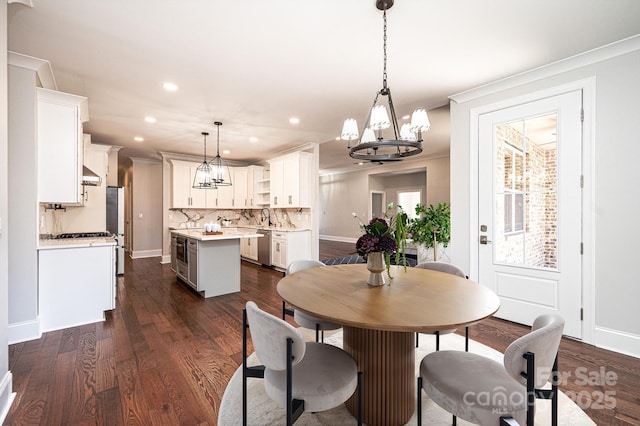 dining space featuring a chandelier, dark wood finished floors, crown molding, and recessed lighting