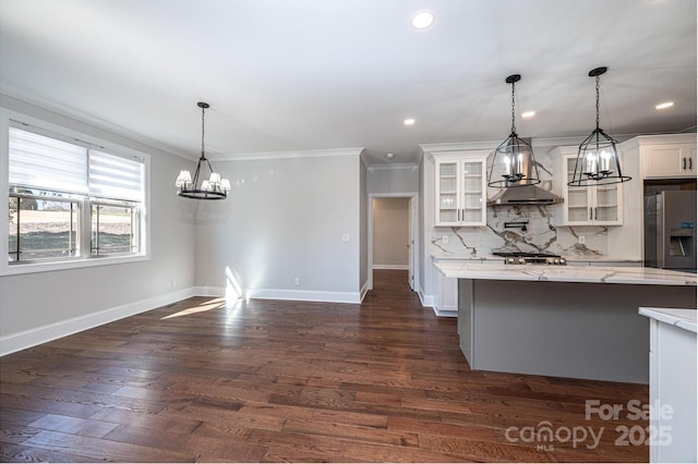 kitchen with tasteful backsplash, glass insert cabinets, hanging light fixtures, white cabinetry, and stainless steel refrigerator with ice dispenser