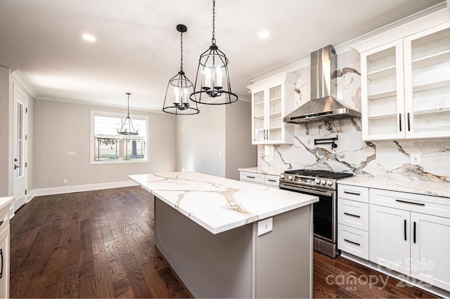 kitchen featuring stainless steel gas range, white cabinetry, glass insert cabinets, and wall chimney range hood