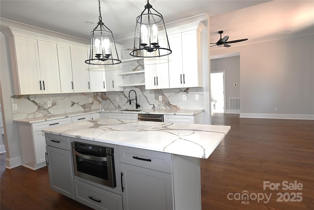 kitchen featuring a kitchen island, appliances with stainless steel finishes, light stone countertops, white cabinetry, and pendant lighting