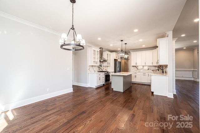 kitchen with a center island, light countertops, hanging light fixtures, white cabinetry, and wall chimney exhaust hood