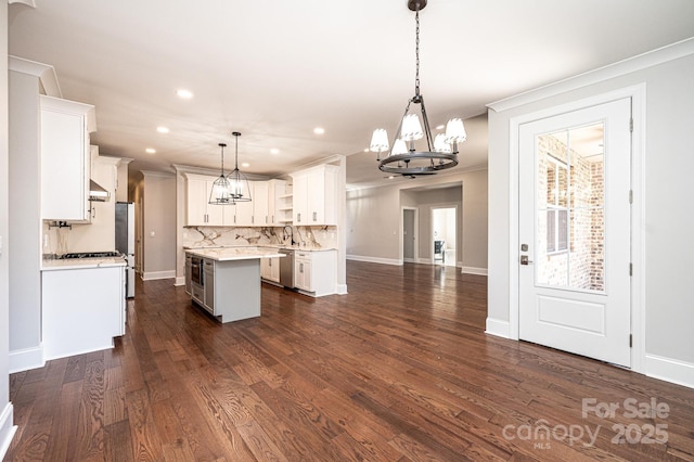 kitchen with a center island, decorative light fixtures, tasteful backsplash, light countertops, and white cabinetry