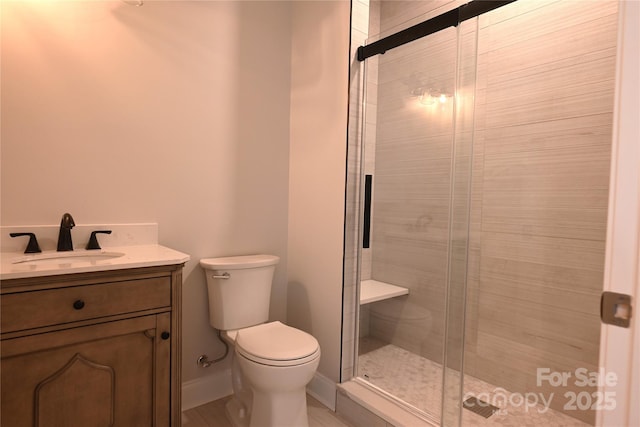 full bath with toilet, a stall shower, baseboards, and vanity