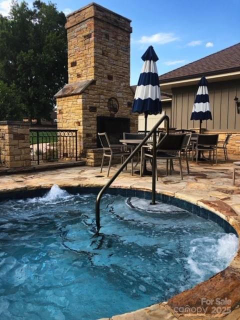 view of swimming pool featuring an outdoor stone fireplace, a patio, and outdoor dining area