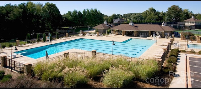 community pool with a patio area and fence