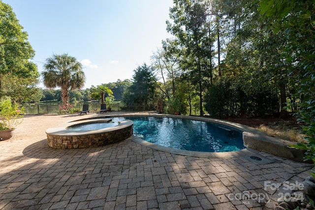 view of pool featuring a patio and an in ground hot tub