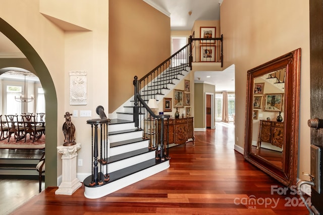 entrance foyer featuring ornamental molding, a chandelier, and dark hardwood / wood-style flooring