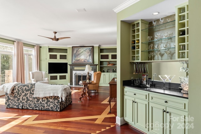 bar with ornamental molding, green cabinetry, ceiling fan, and dark hardwood / wood-style flooring