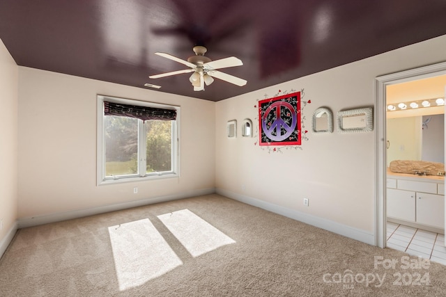 unfurnished bedroom with ceiling fan, light colored carpet, and ensuite bath