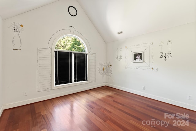 spare room with wood-type flooring and lofted ceiling