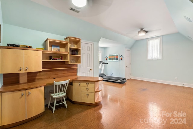 unfurnished office with built in desk, lofted ceiling, ceiling fan, and hardwood / wood-style floors