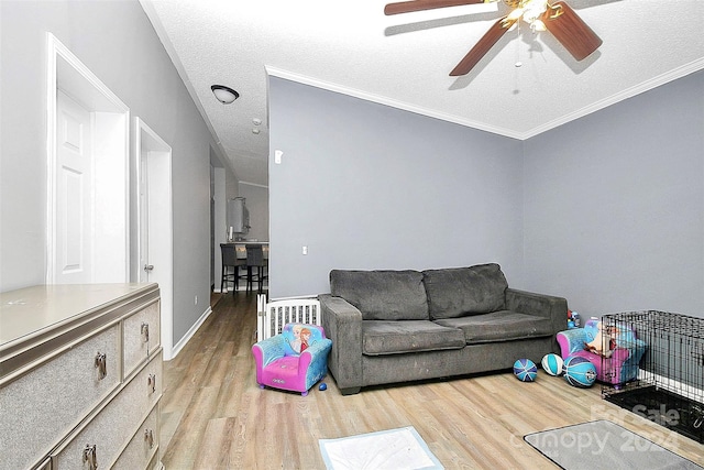 living room with a textured ceiling, light hardwood / wood-style floors, ornamental molding, and ceiling fan