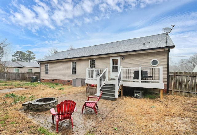 rear view of house featuring central AC unit, a deck, and an outdoor fire pit