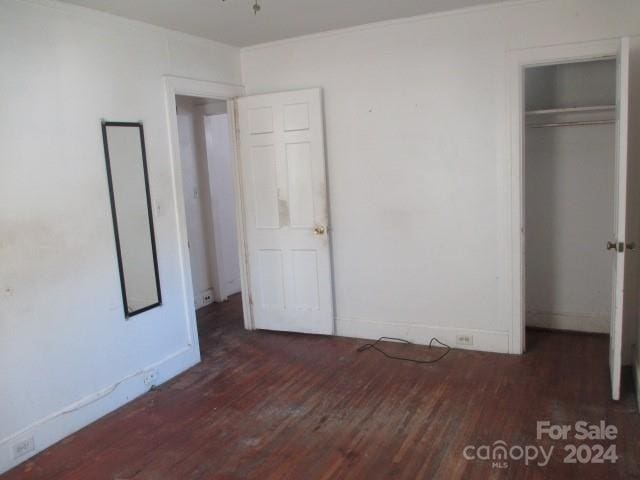 unfurnished bedroom with dark hardwood / wood-style flooring and a closet