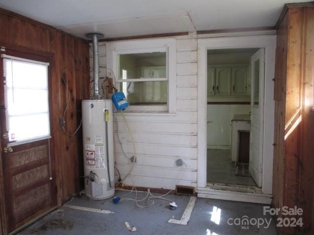 interior space featuring water heater and wooden walls