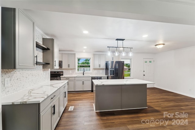 kitchen featuring pendant lighting, appliances with stainless steel finishes, a kitchen island, and dark hardwood / wood-style flooring