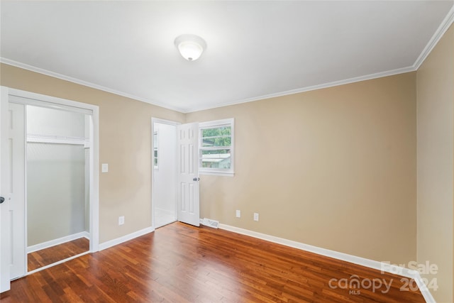 unfurnished bedroom featuring a closet, crown molding, and hardwood / wood-style floors