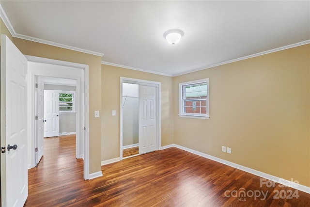 unfurnished bedroom featuring ornamental molding, a closet, and dark hardwood / wood-style flooring