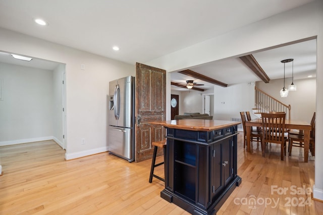 kitchen with a kitchen bar, stainless steel fridge, a kitchen island, and light wood-type flooring