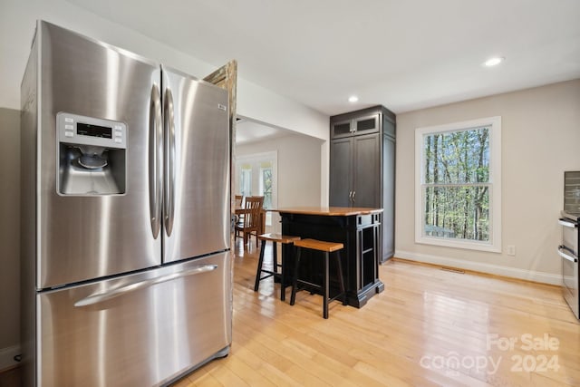 kitchen featuring a breakfast bar, light hardwood / wood-style floors, and stainless steel refrigerator with ice dispenser