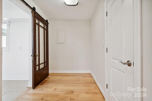 hall featuring a barn door and light hardwood / wood-style floors