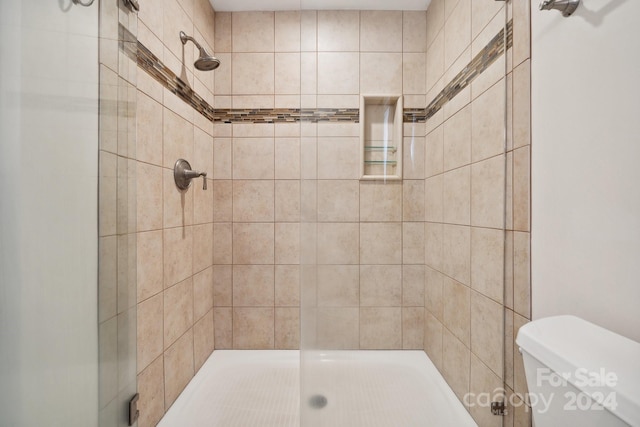 bathroom with tiled shower and toilet