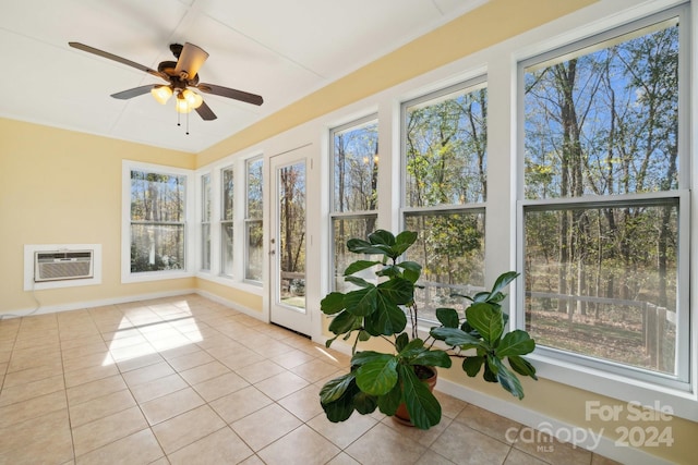 unfurnished sunroom with ceiling fan, a wall unit AC, and a wealth of natural light