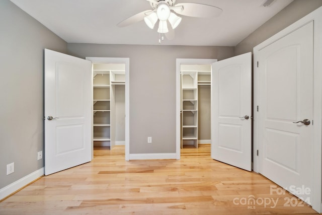 unfurnished bedroom with a walk in closet, light hardwood / wood-style floors, and ceiling fan