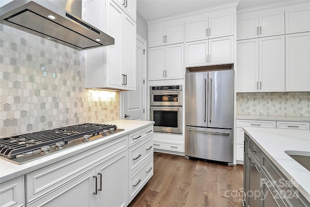 kitchen featuring light stone counters, dark wood-type flooring, white cabinetry, stainless steel appliances, and range hood