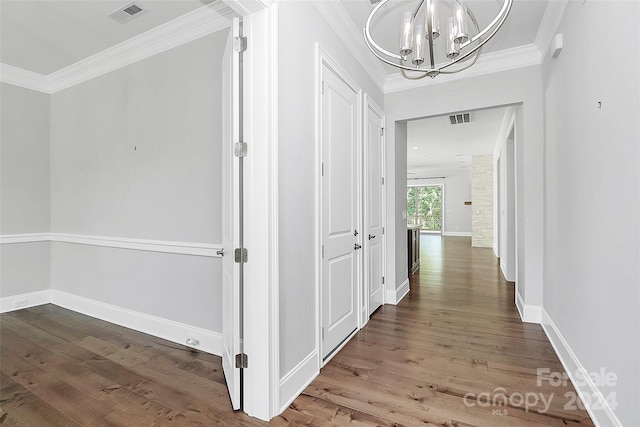 hallway with a notable chandelier, wood-type flooring, and ornamental molding