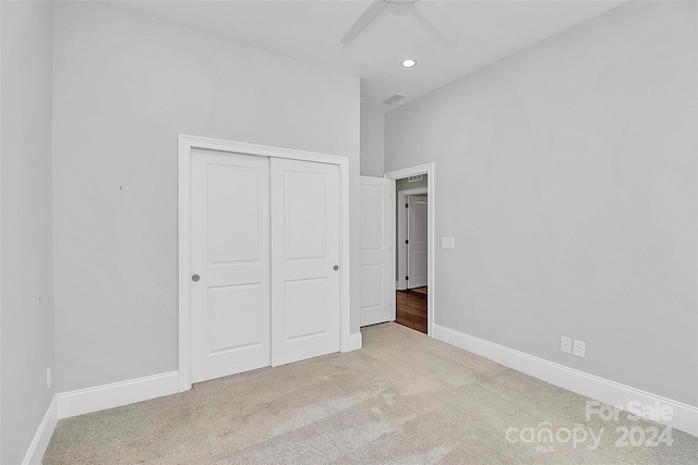 unfurnished bedroom with light carpet, a closet, and ceiling fan