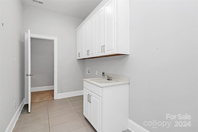 clothes washing area with cabinets, washer hookup, light tile patterned flooring, and sink