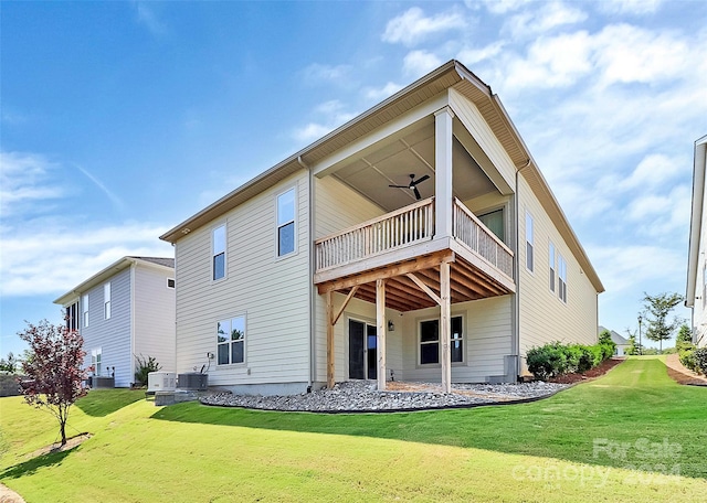 rear view of house with a balcony, central AC, and a yard