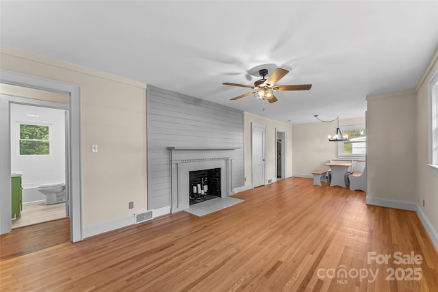 unfurnished living room with wood-type flooring, a large fireplace, and a wealth of natural light